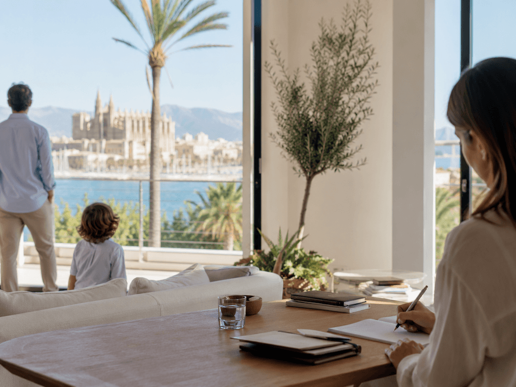 Familie auf einer mediterranen Terrasse mit Blick auf Palma; im Vordergrund Beraterin am Tisch